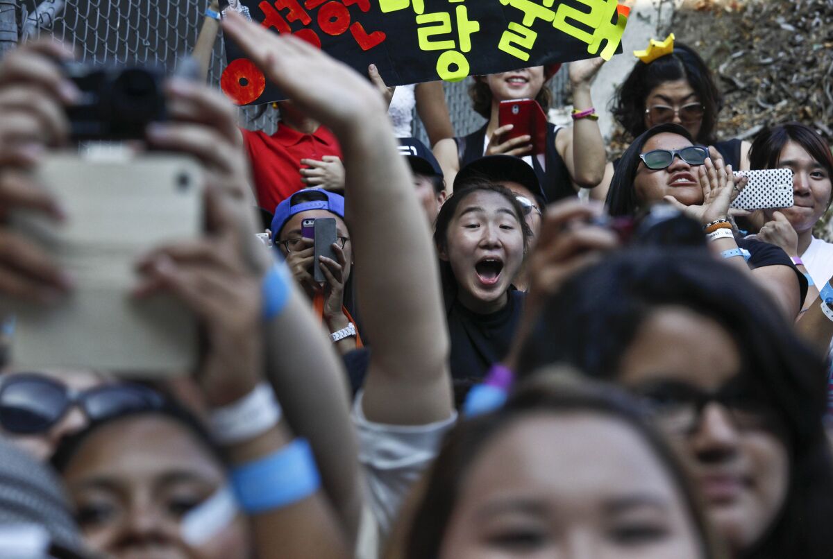 Fans scramble to get photographs of K-pop supergroups during a meet-and-greet before a concert at the Los Angeles Sports Arena.