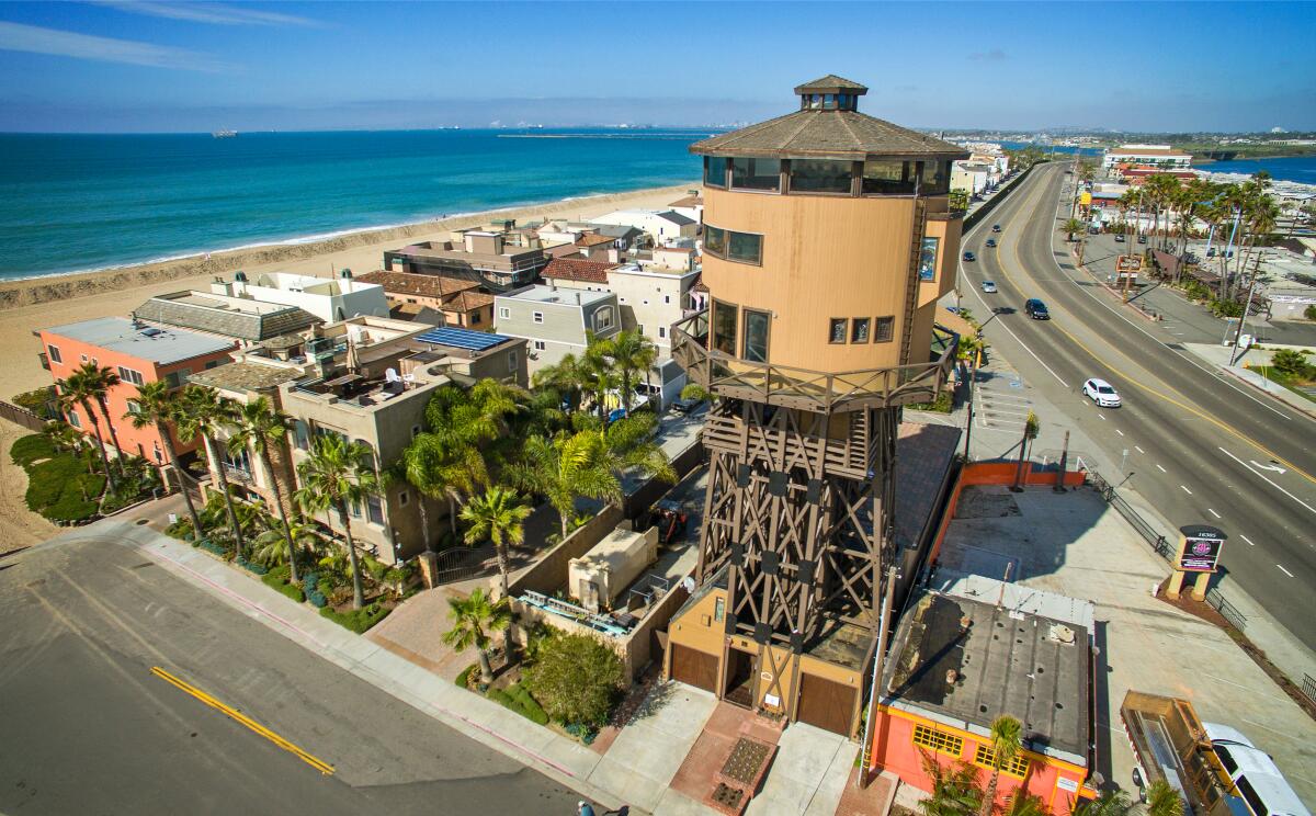 House on scaffold base surrounded by shorter houses with ocean and beach to the left