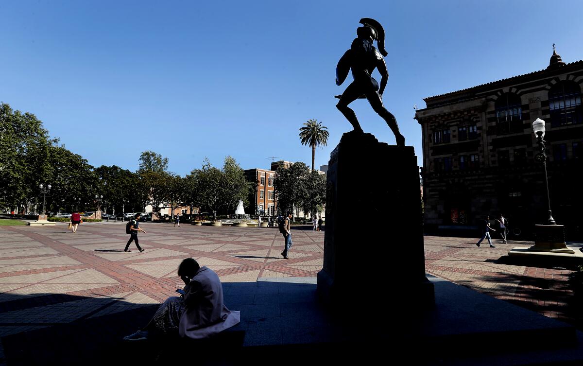 USC students walk past Tommy Trojan statue on campus. 