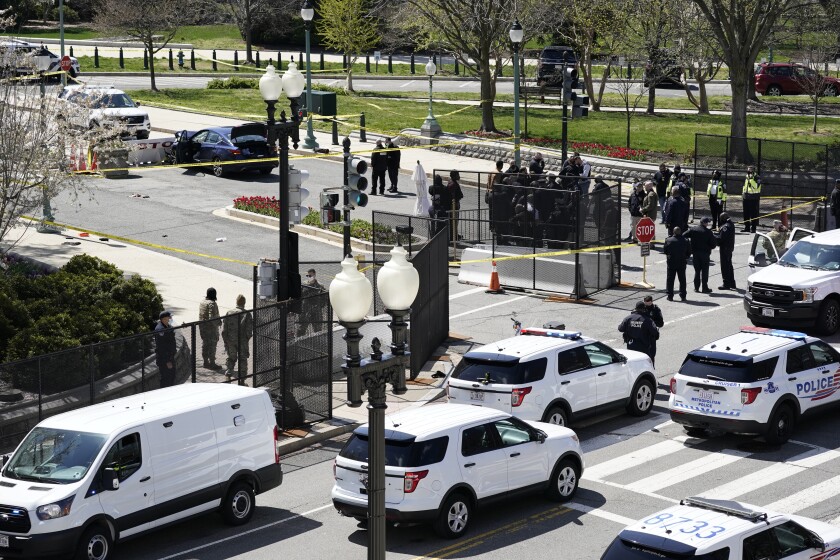 Police officers gather near a car that crashed into a barrier on Capitol Hill in Washington, Friday, April 2, 2021.