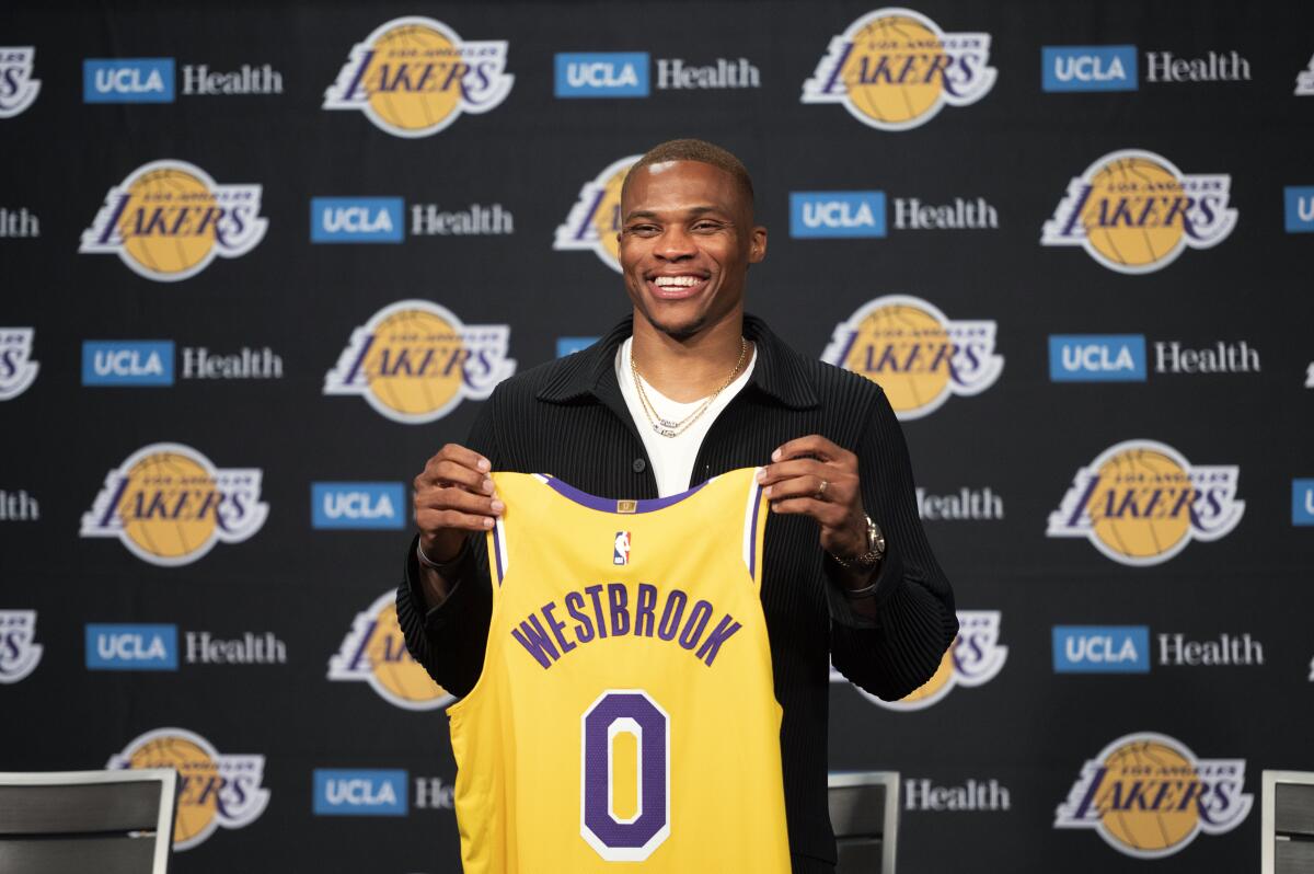Los Angeles Lakers guard Russell Westbrook poses for a photo with his jersey at an introductory NBA basketball news conference in Los Angeles, Tuesday, Aug. 10, 2021. (AP Photo/Kyusung Gong)