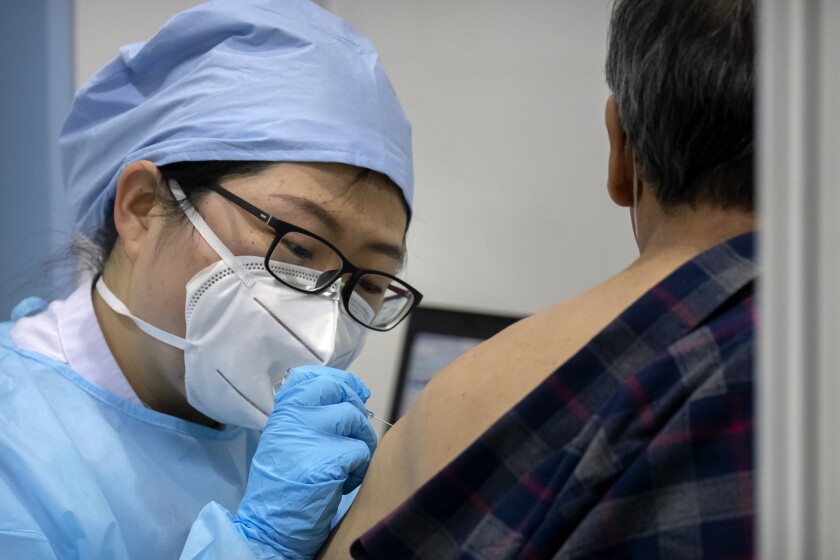 A medical worker gives a coronavirus vaccine shot to a patient at a vaccination facility in Beijing, Friday, Jan. 15, 2021. A city in northern China is building a 3,000-unit quarantine facility to deal with an anticipated overflow of patients as COVID-19 cases rise ahead of the Lunar New Year travel rush. (AP Photo/Mark Schiefelbein)