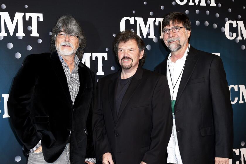 Three men from musical group Alabama standing in front of CMT red carpet banner 