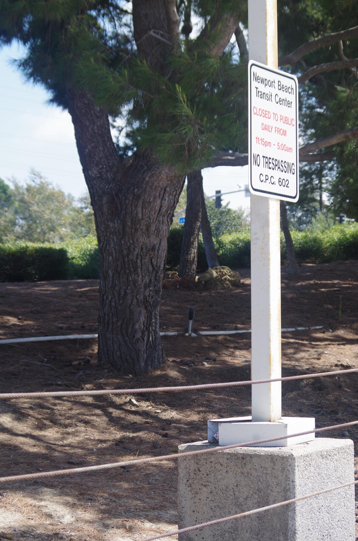A new "No trespassing" sign at the Newport Beach transit center on Avocado Avenue posts the hours the station is closed to the public. Tents housing homeless people were on the slope behind the sign until police removed them late Wednesday.