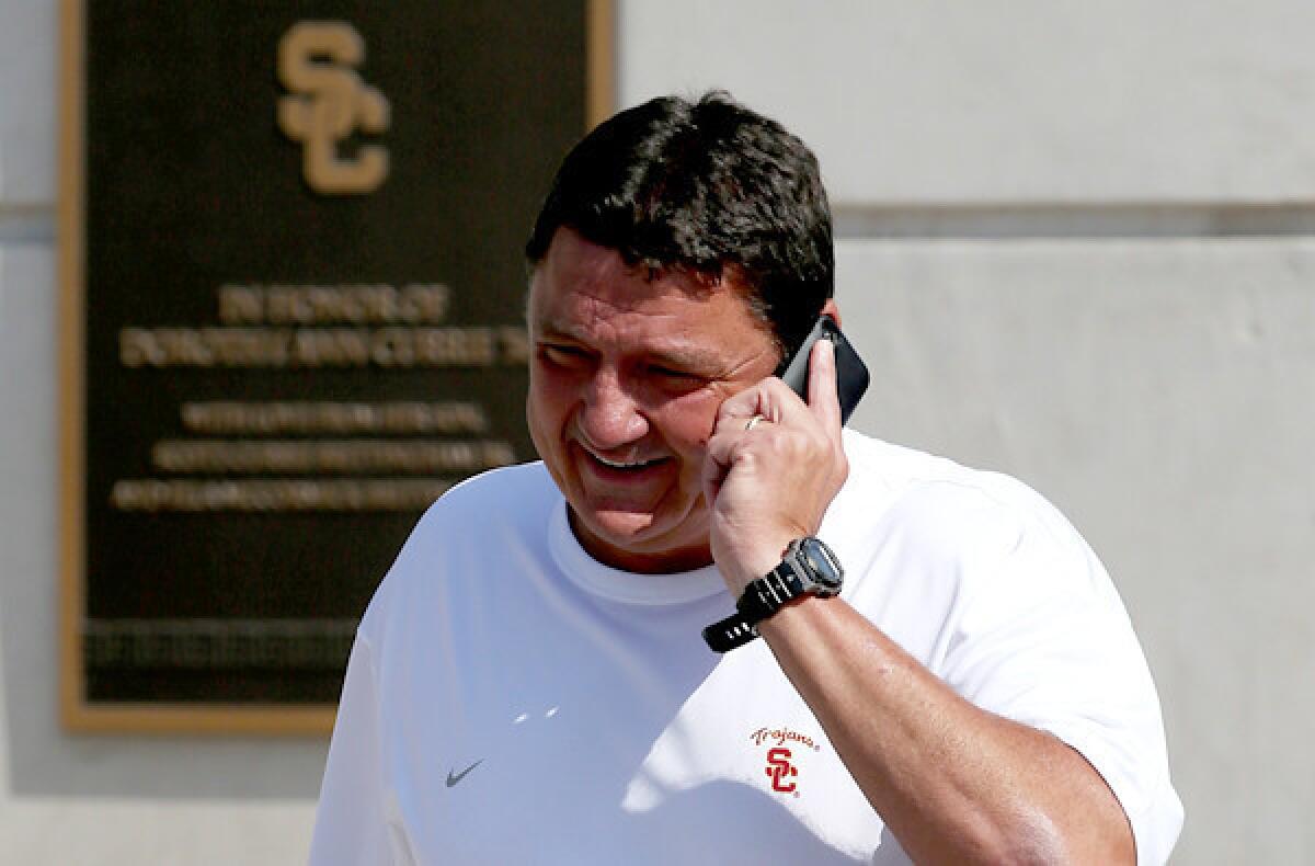 Ed Orgeron, USC's interim football coach, chats on the phone while walking to the practice field Wednesday.