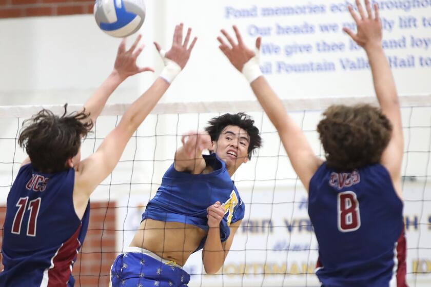Fountain Valley's Thomas Ho, center, hits a kill past the blocks of Jacob Johnson (11) and Brandin Mackin (8) from Capistrano Valley Christian during second round of the CIF Southern Section Division 3 playoffs on Monday.