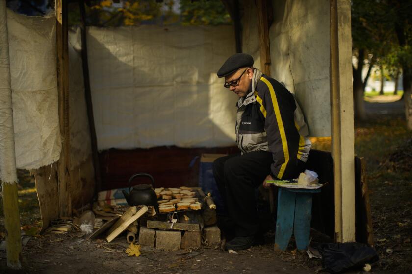 Anton Sevrukov, 47, toasts bread over fire in a makeshift stove in Kivsharivka, Ukraine, Sunday, Oct. 16, 2022. As temperatures drop below freezing in eastern Ukraine, those who haven't fled from the heavy fighting, regular shelling and months of Russian occupation are now on the threshold of a brutal winter and digging in for the cold months. (AP Photo/Francisco Seco)
