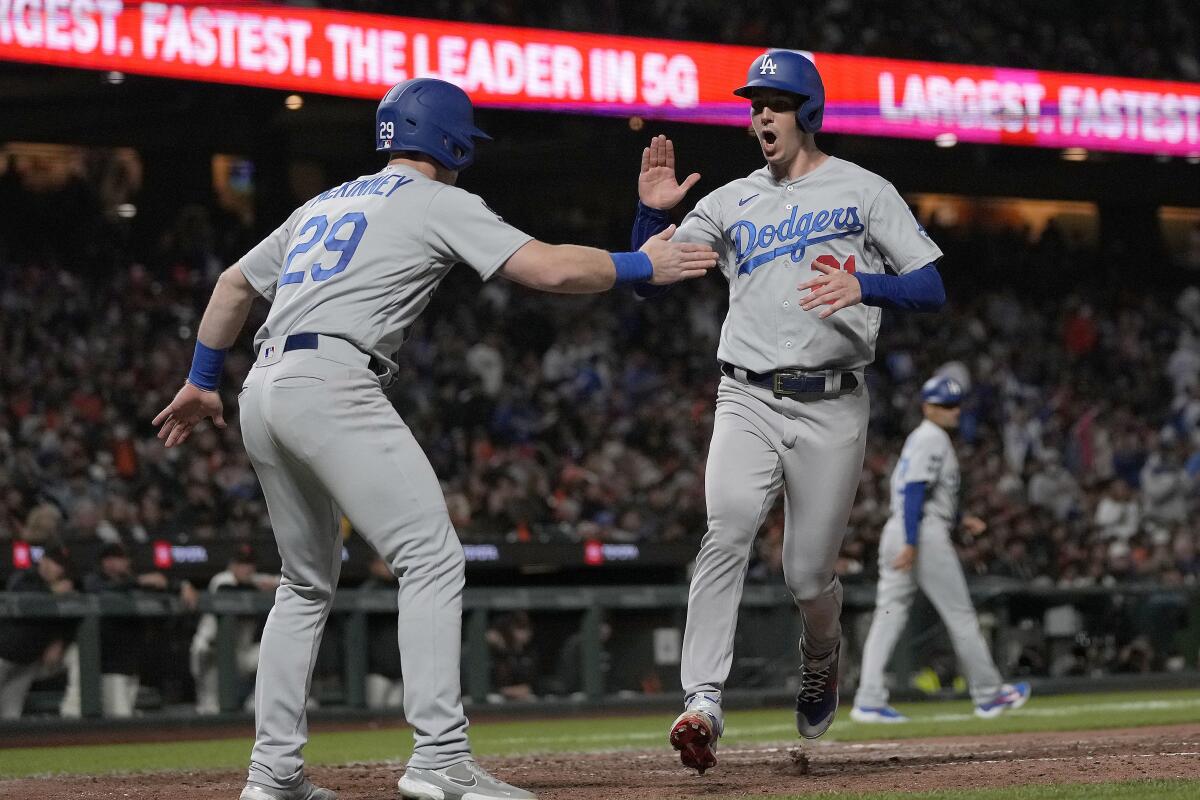 Dodgers' Walker Buehler celebrates with Billy McKinney after both scored on a double by Max Muncy.