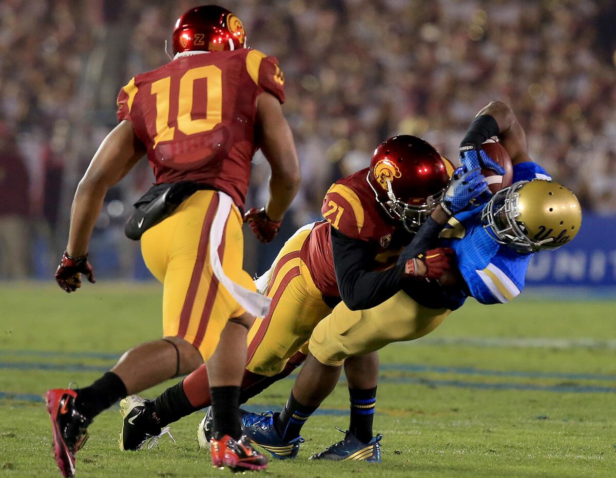 UCLA receiver Mossi Johnson holds on to a pass for a first down despite receiving a big hit from USC linebacker Su'a Cravens during the second quarter Saturday night at the Rose Bowl.