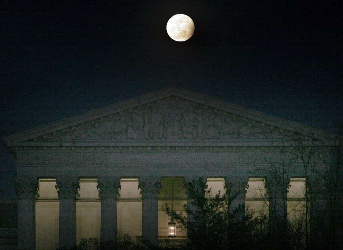 The moon, in penumbral lunar eclipse, rises over the U.S. Supreme Court in Washington, D.C., in 2006.
