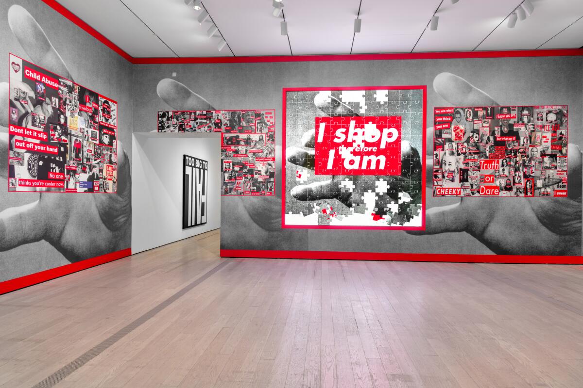A gallery covered in wallpaper shows large human hands holding collages of images inspired by Barbara Kruger's work 