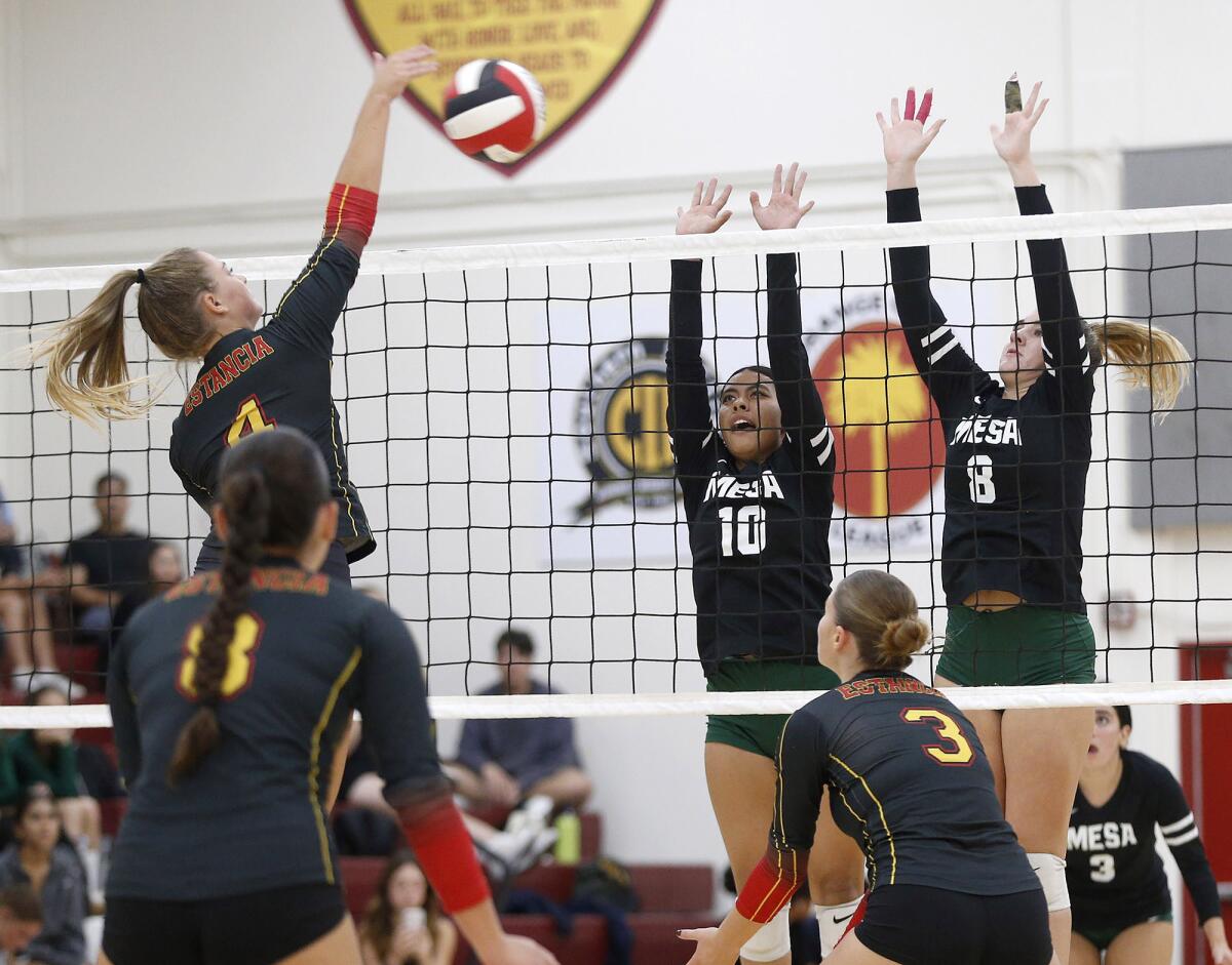 Estancia's Jenna Schroeder (4) kills a ball past the blocks of Costa Mesa's Jamie Kibin (10) and Lucca Miller (8) on Tuesday.