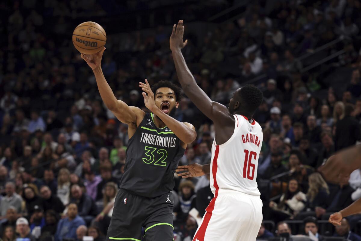 Minnesota Timberwolves center Karl-Anthony Towns (32) passes the ball away from Houston Rockets forward Usman Garuba (16) during the first half of an NBA basketball game Saturday, Nov. 5, 2022, in Minneapolis. (AP Photo/Stacy Bengs)