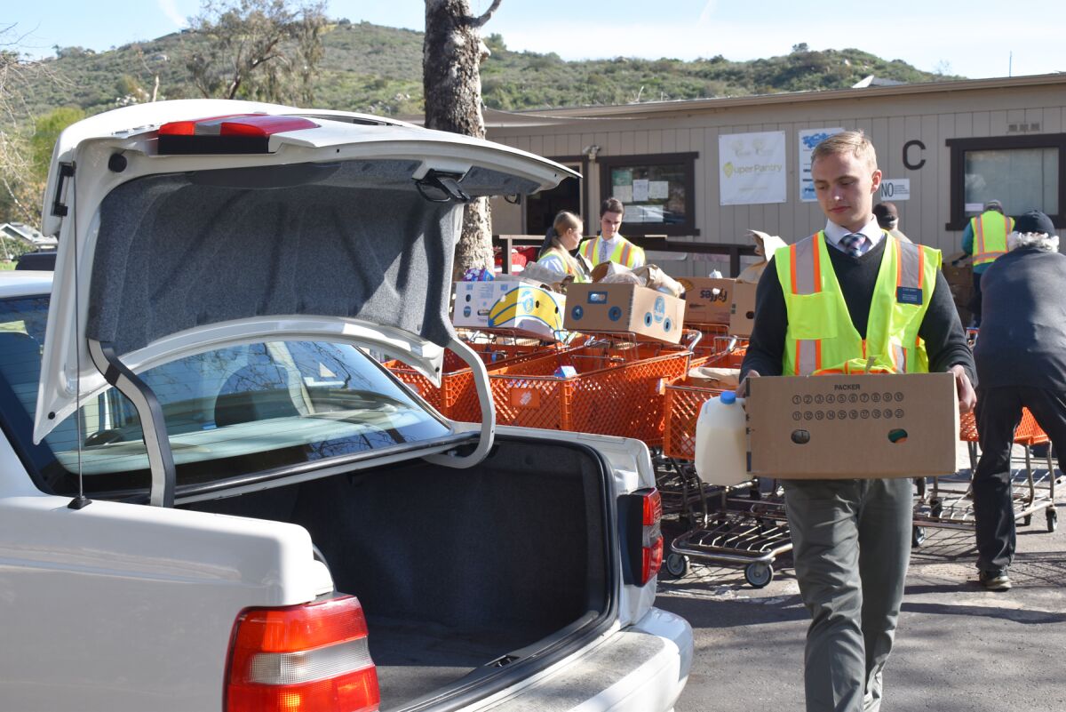Volunteer Boden Quiner carrying food to a vehicle at The Community Food Connection.