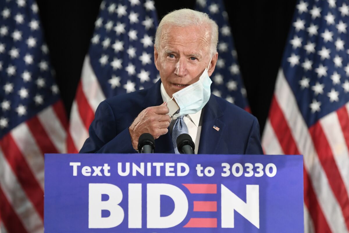 Former Vice President Joe Biden takes off his mask before speaking Friday in Dover, Del.
