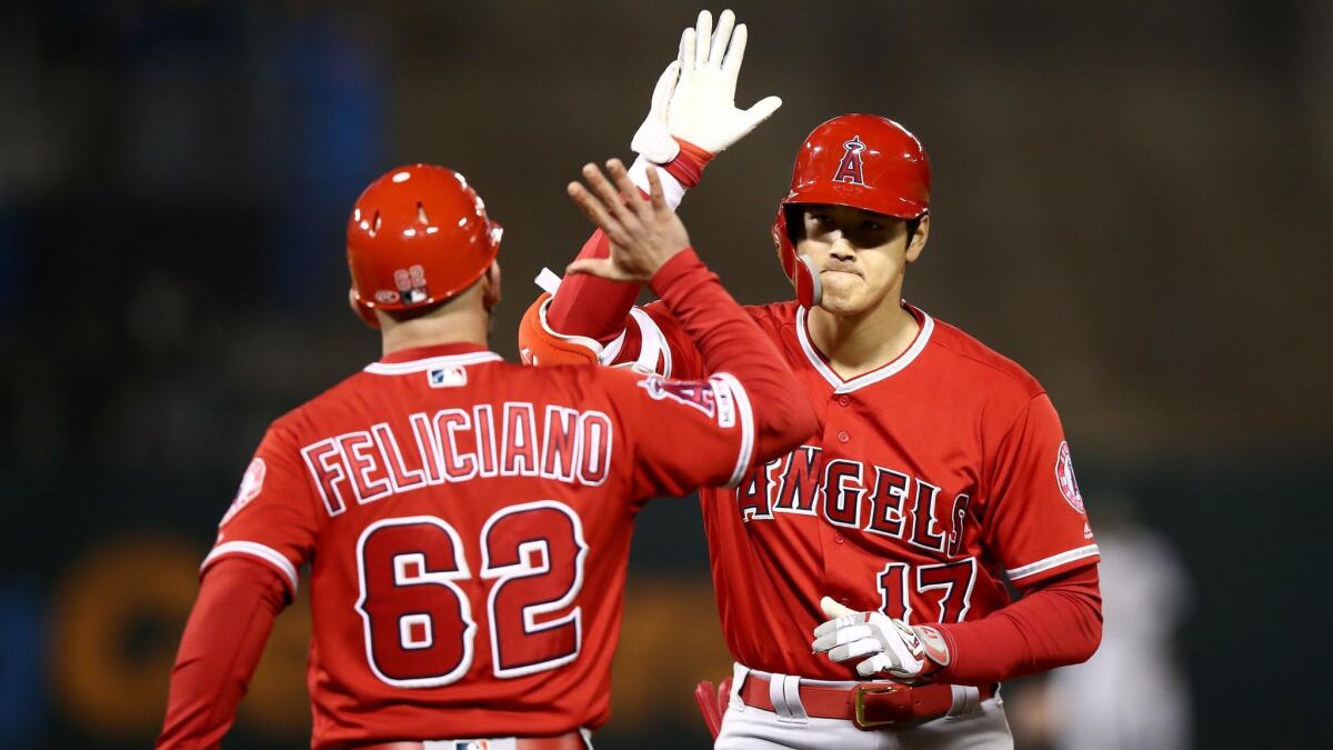 Shohei Ohtani is congratulated by first base coach Jesus Feliciano after hitting a single that scored two runs in the ninth inning against the Athletics on Tuesday in Oakland.