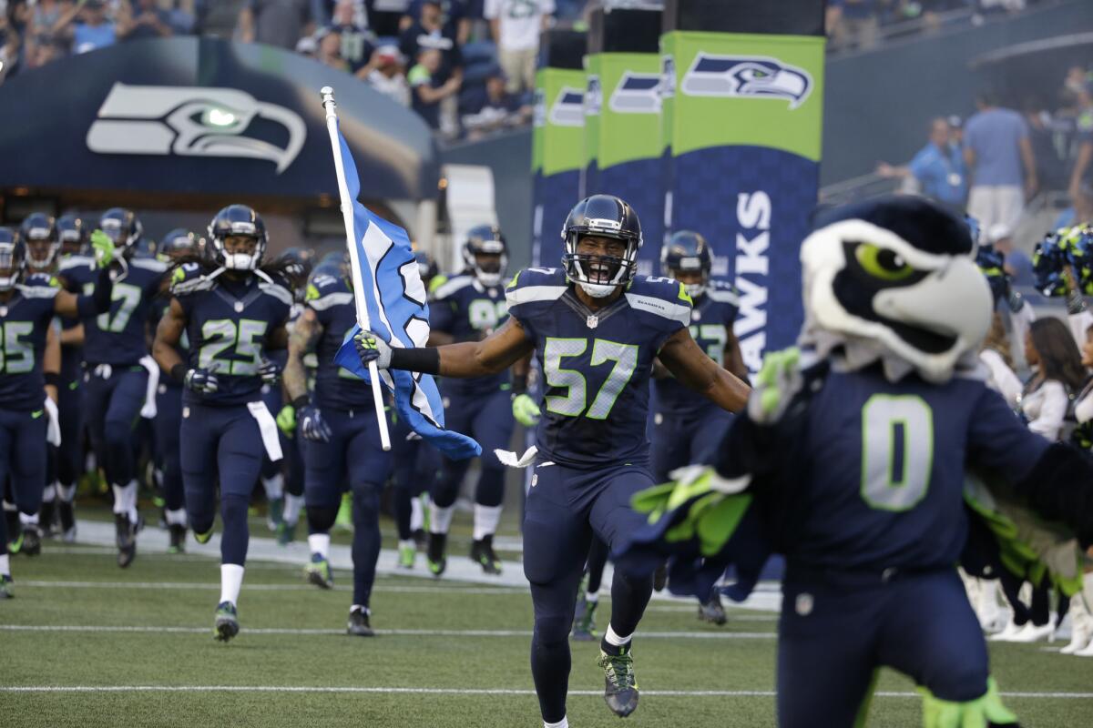 Seahawks outside linebacker Mike Morgan (57) runs with the Seahawks' 12 flag before a preseason game against the Cowboys on Aug. 25.