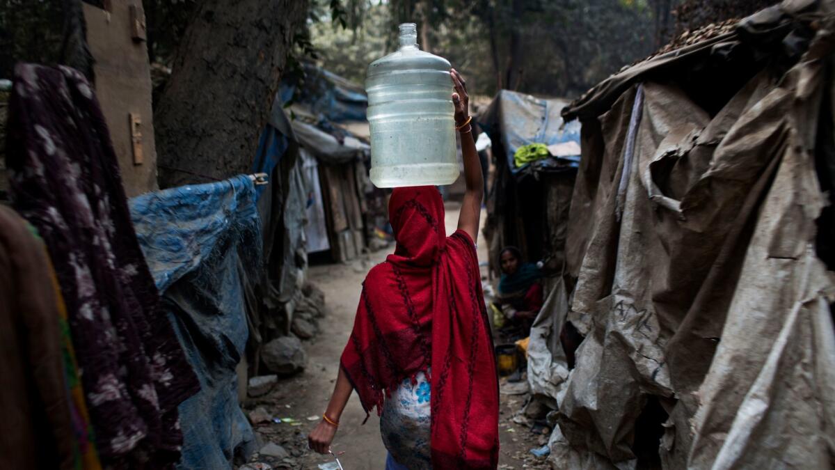 An Indian woman carries a plastic container filled with water in a slum area of New Delhi.