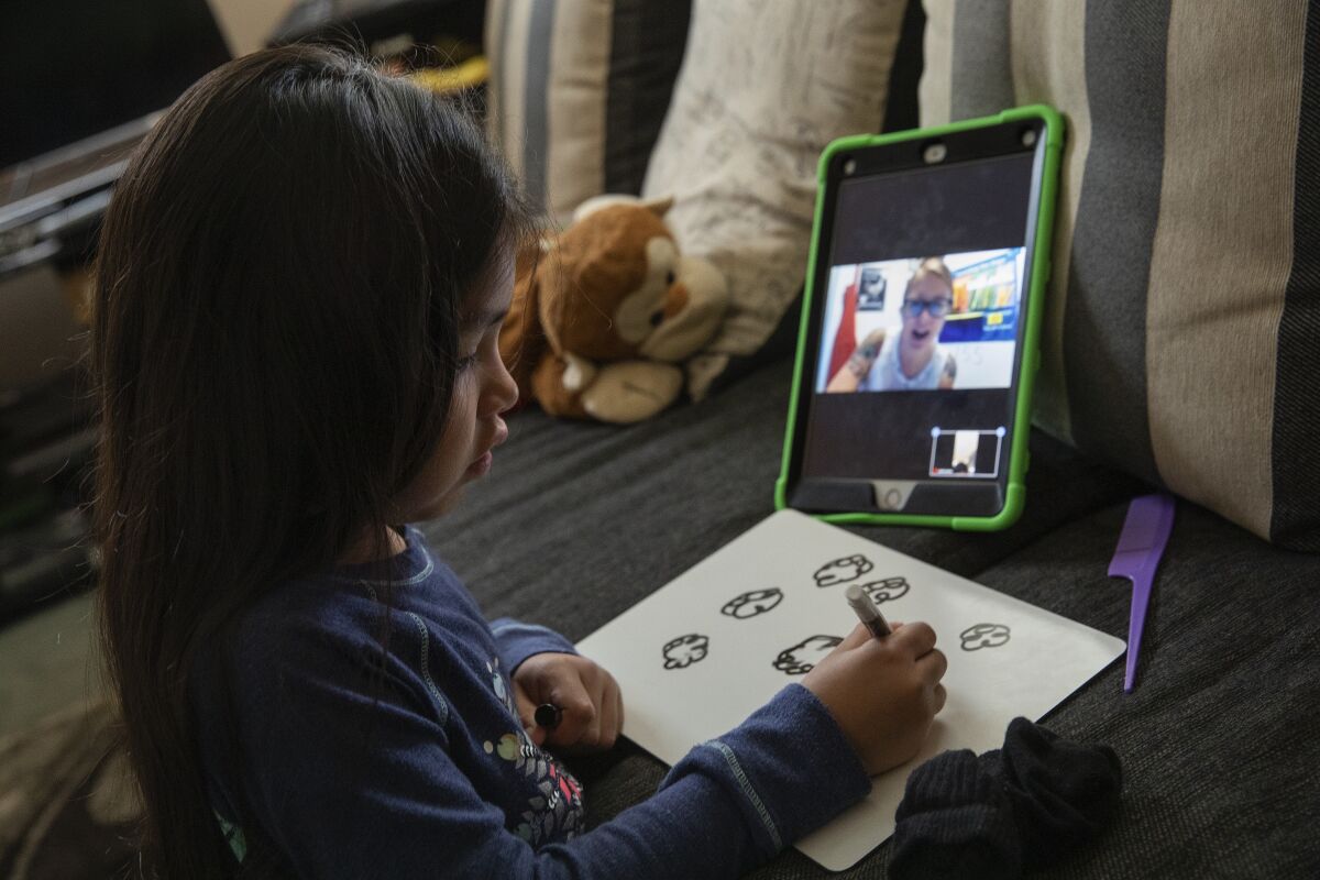 A girl talks to her teacher during a zoom class.