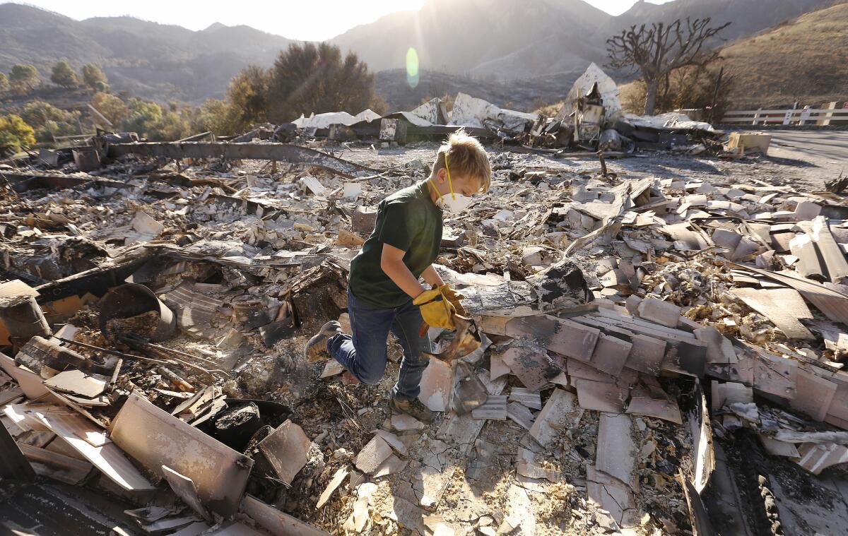 Nine-year-old Landon Quirk came with his father, Trevor Quirk, to help search through the rubble of a friend's home in the Seminole Springs Mobilehome Park on Mulholland Drive in Agoura Hills destroyed by the Woolsey fire.