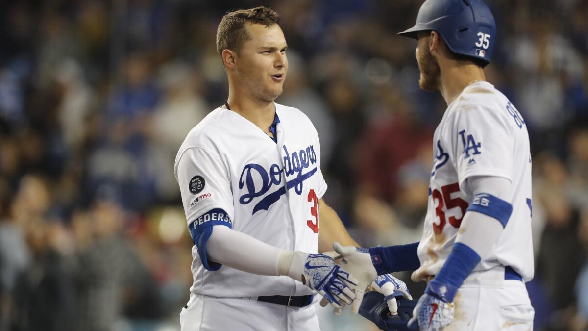 Dodgers outfielder Joc Pederson, left, is congratulated by teammate Cody Bellinger after hitting a solo home run against the Philadelphia Phillies in the fifth inning on Friday at Dodger Stadium.