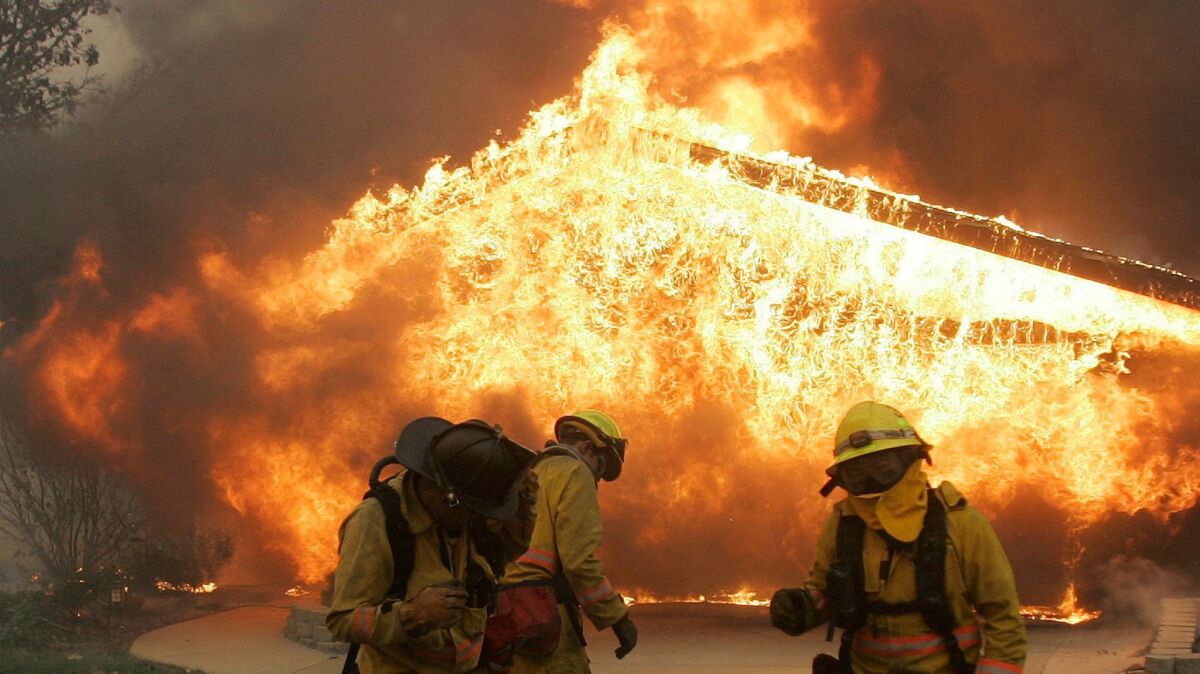 A home burns during a 2007 San Diego wildfire, which still weighs on San Diego Gas & Electric Co. Last month, state regulators forced San Diego utility shareholders, not ratepayers, to pay $379 million in costs from three 2007 fires ignited by power lines.