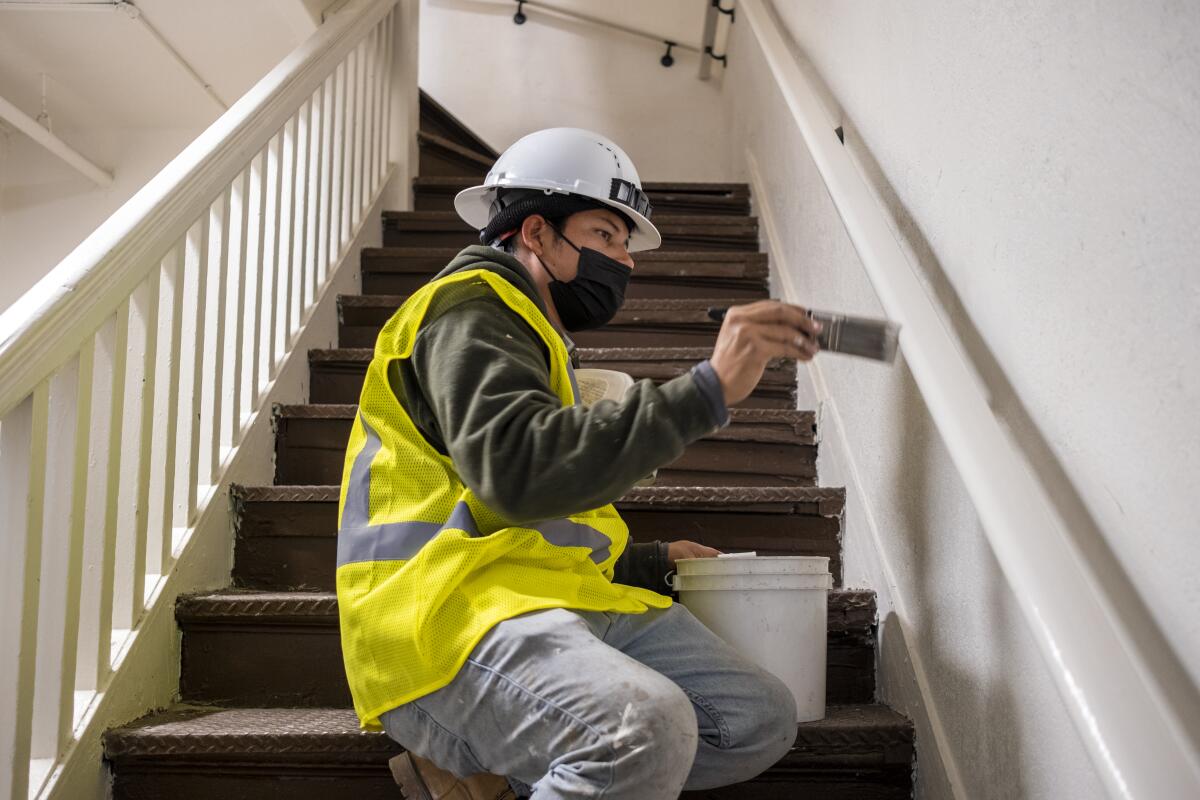 A person kneeling on a staircase while painting