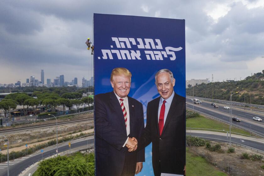 FILE - In this Sept. 8, 2019, file photo, a worker hangs an election campaign billboard of the Likud party showing U.S. President Donald Trump, left, and Israeli Prime Minister Benjamin Netanyahu in Tel Aviv. Netanyahu’s recent troubles have some parallels to those of his good friend Trump. Both face an array of corruption allegations, both have lashed out at the media and investigators, and both suffered major setbacks this week at the hands of career government officials. (AP Photo/Oded Balilty, File)