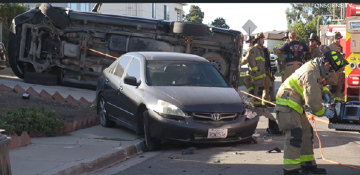 San Diego firefighters work at the scene of a fatal rollover crash in Oak Park.