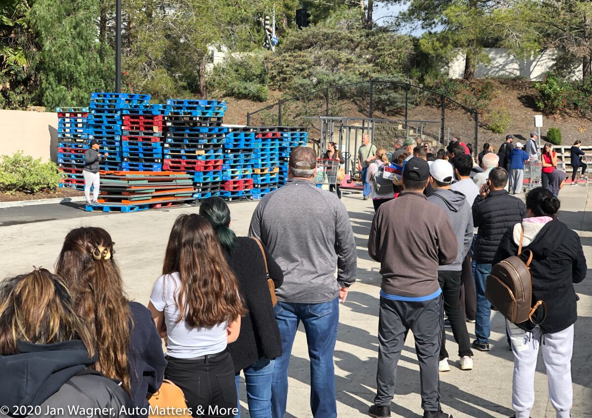 Long line of people waiting to get in to a store.