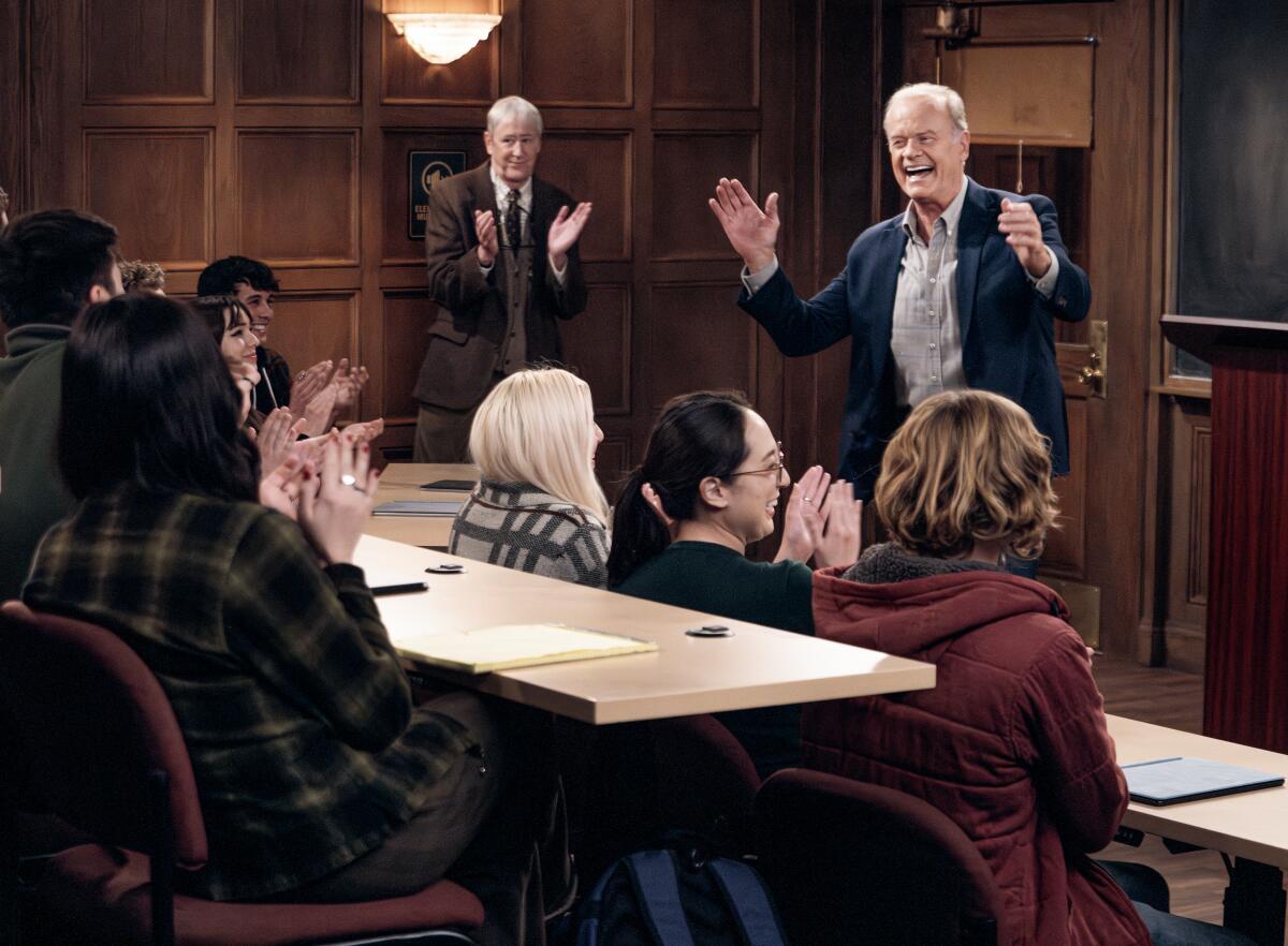 Alan and Frasier stand at the front of a classroom as college students sit and clap.