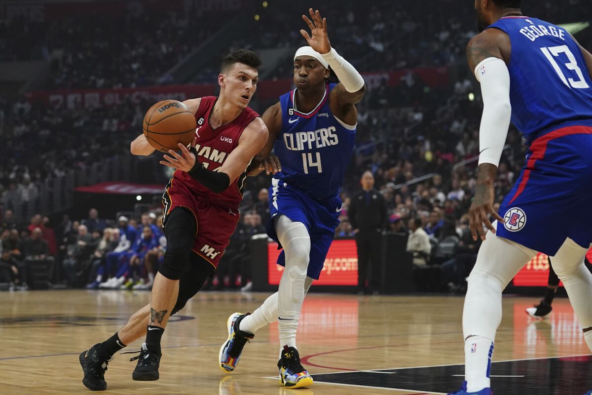 miami heat guard tyler herro drives to the basket against clippers guard terrence mann.