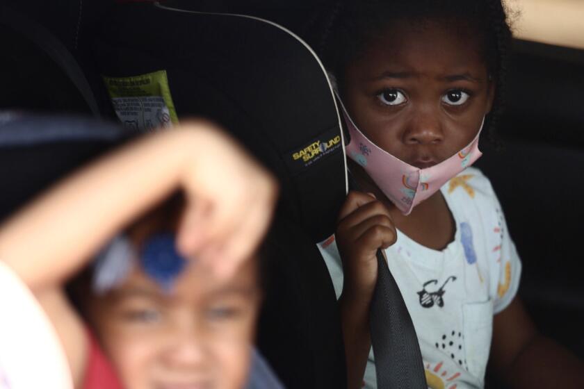 CARSON, CA - APRIL 28, 2020 - - Carson residents Kaeli Burks, 3, left, and her cousin Bailey Watson, 5, look out the window of their car after their mothers helped them with self-testing at a new drive-up testing site for COVID-19 outside the East Wing of the Congresswoman Juanita Millender-McDonald Community Center in Carson on April 28, 2020. Free COVID-19 testing is available to all city residents thanks to a partnership between the city and US Health Fairs. Carson is the first Southern California city to offer free testing to all its residents. Mayor Albert Robles and members of the City Council will be joined by Assemblyman Mike A. Gipson, D-Carson, for the test site opening. (Genaro Molina/Los Angeles Times)