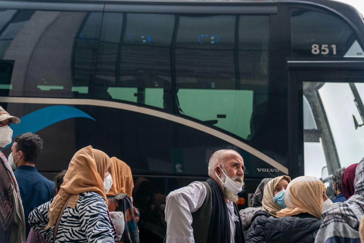 Weary-looking evacuees line up to board a bus 