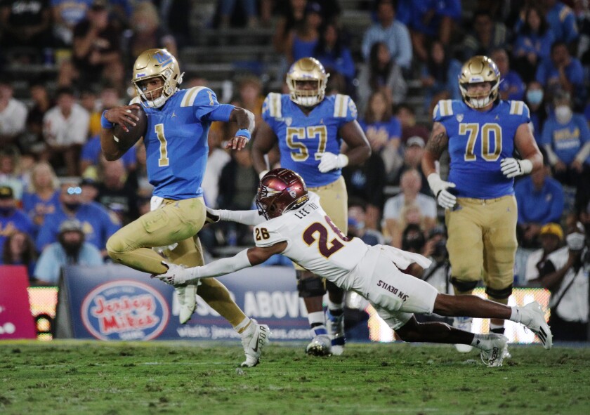 UCLA quarterback Dorian Thompson-Robinson sprints ahead of diving Arizona State defensive back T Lee.