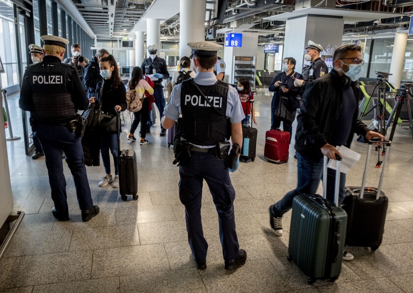 Police officers check passengers at an airport.