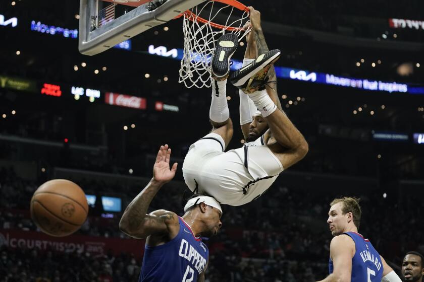 Brooklyn Nets' DeAndre' Bembry, top center, bumps into Los Angeles Clippers' Eric Bledsoe as he swings from the rim after dunking during first half of an NBA basketball game Monday, Dec. 27, 2021, in Los Angeles. (AP Photo/Jae C. Hong)