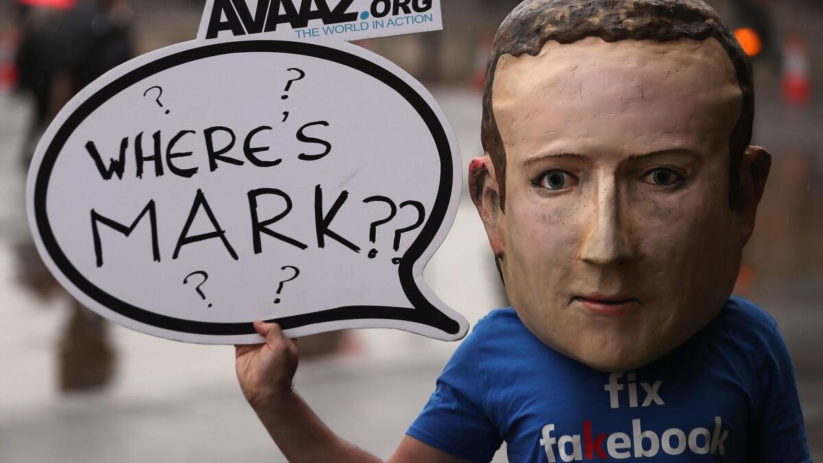 A person wearing a mask of Facebook CEO Mark Zuckerberg protests in London on Tuesday, criticizing Zuckerberg's unwillingness to testify before lawmakers.