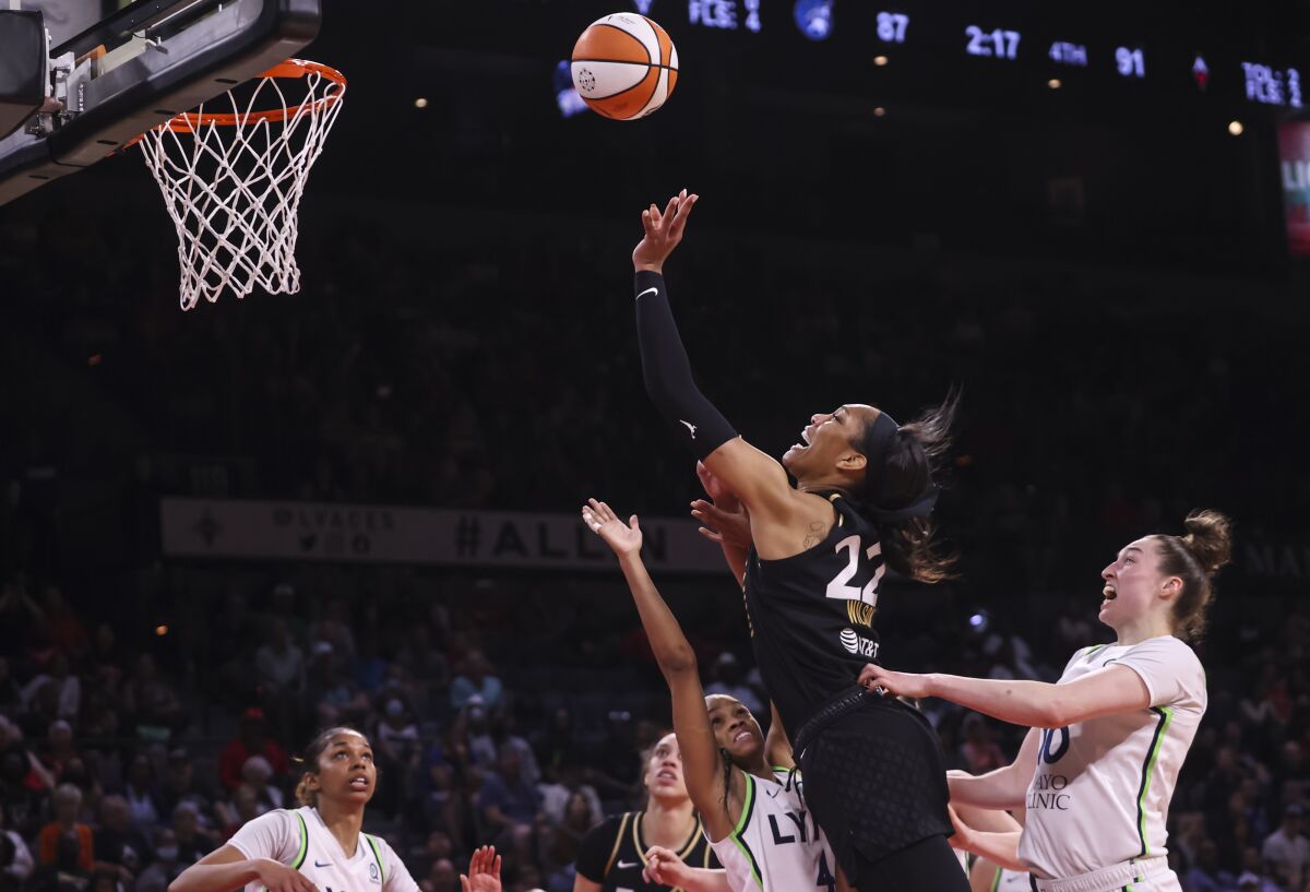 Las Vegas Aces forward A'ja Wilson (22) lays up the ball between Minnesota Lynx guard Moriah Jefferson (4) and forward Jessica Shepard (10) during the second half of a WNBA basketball game Sunday, June 19, 2022, in Las Vegas. (Chase Stevens/Las Vegas Review-Journal via AP)