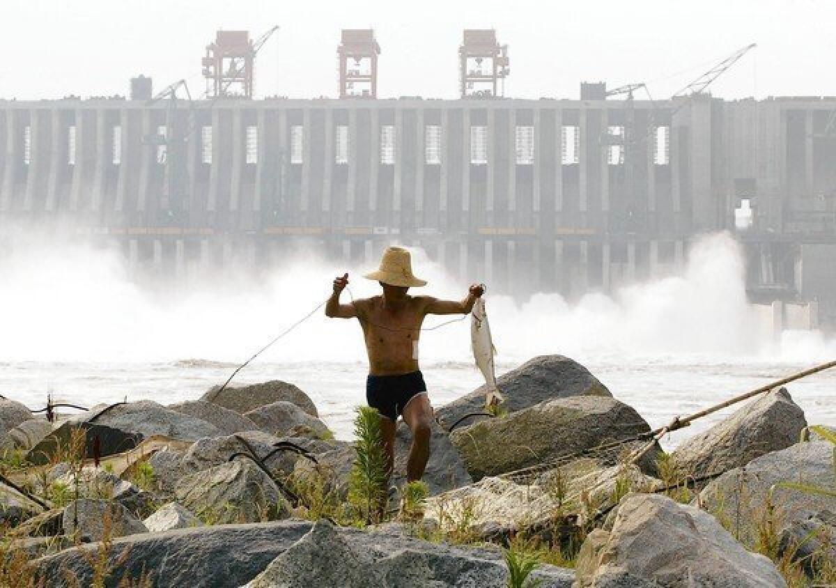 A Chinese man carries a fish he caught below the spillway of the Three Gorges Dam on the Yangtze River, near Yichang, in central China's Hubei province on June 13, 2003.
