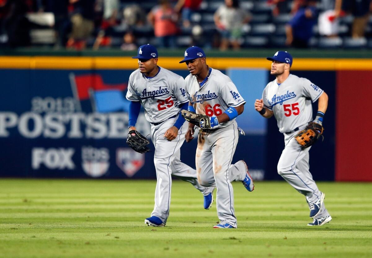 Carl Crawford, Yasiel Puig and Skip Schumaker, left to right, run to the dugout after defeating the Braves in Game 1 of the National League Division Series at Turner Field in Atlanta.