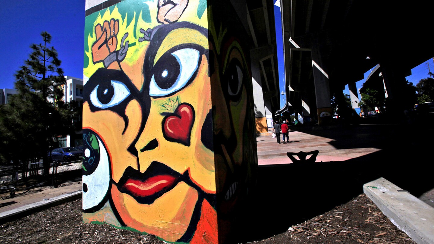 Barrio Logan residents walk past columns covered with murals through Chicano Park under the Coronado Freeway bridge near Newton Avenue. The park was created after the bridge cut the community in half and residents pressured the government to give them some green space.