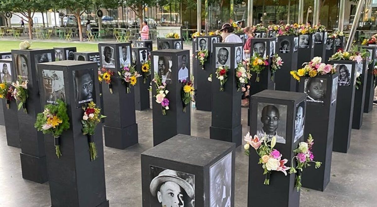 The "Say Their Names" exhibit in Dallas last year featured photos and flowers on square pillars.