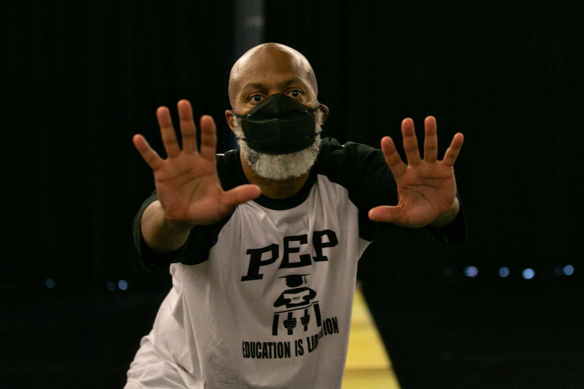 A man wearing a KN-95 mask rehearses a dance.