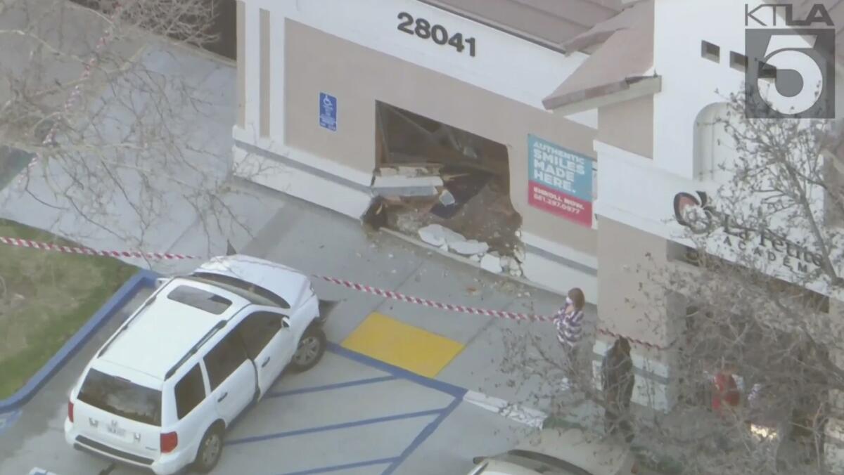 An SUV next to a building with a hole in its wall