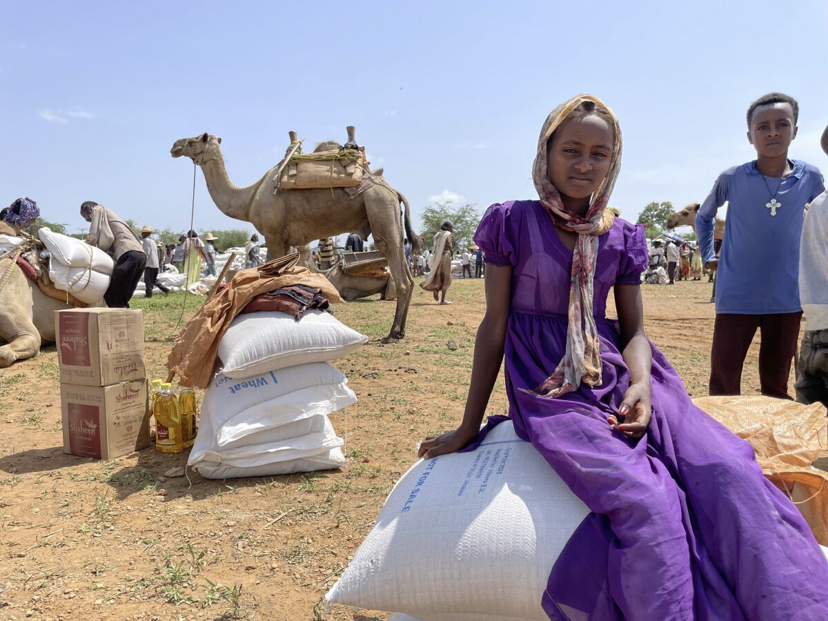 A young Tigrayan girl sits on sacks of wheat after the World Food Programme (WFP) distributed food to around 13,000 people in the rural village of Zelazle in the Tigray region of northern Ethiopia Monday, Aug. 23, 2021. (Claire Nevill/WFP via AP)