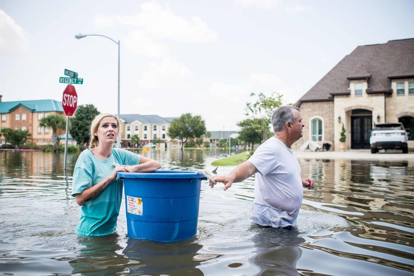 Jenna Fountain and her father Kevin carry a bucket down Regency Drive to try to recover items from their flooded home in Port Arthur, Texas on Thursday.