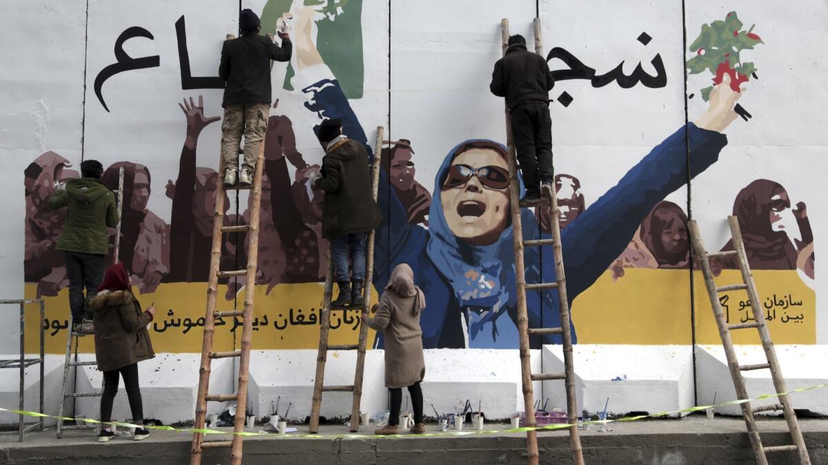 Independent Afghan artists paint a mural on a barrier wall of the Ministry of Women's Affairs to mark International Women's Day in Kabul on Friday.