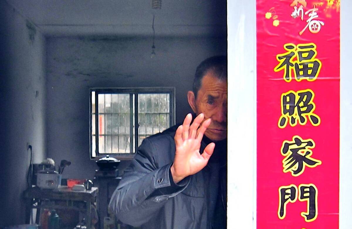 Qiu Riren, facing a prison sentence for the murder of a doctor during the Cultural Revolution, stands in the doorway of his home, waving off visitors. 3/28/2013.