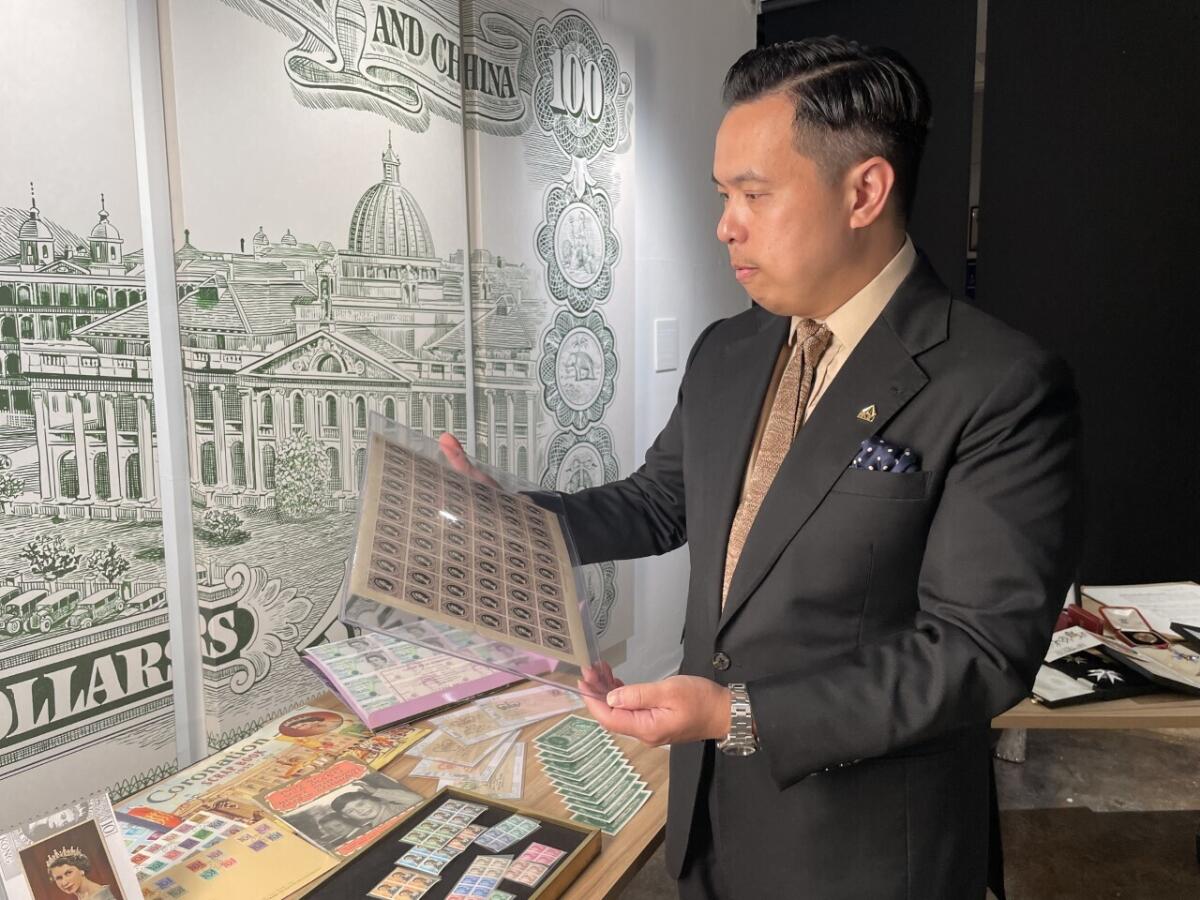 Museum owner Bryan Ong looks at old postage stamps from British Hong Kong, at the private museum The Museum Victoria City, that showcases royal items like postcards, commemorative coins, old banknotes, old postage stamps and various memorabilia in Hong Kong, on Sept. 10, 2022. Ong said the Hong Kong people feel an emotional connection to the Queen because of the colonial history of the city. (AP Photo/Alice Fung)